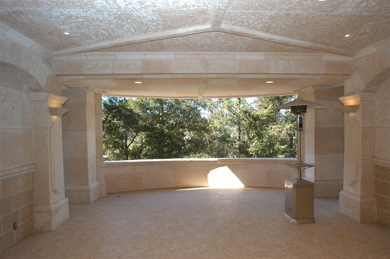 Interior colonnade and coffered ceiling framing a wide window onto trees