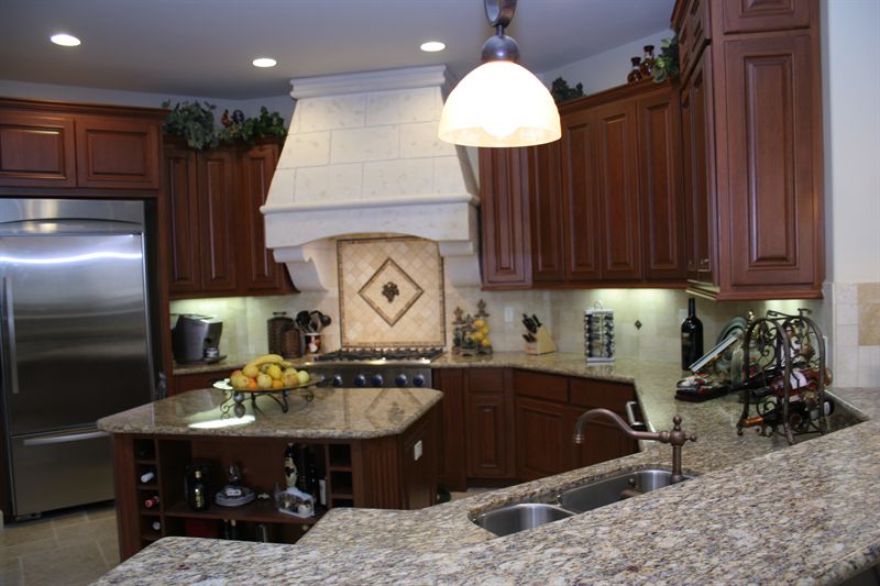 Kitchen with dark cherry cabinetry, granite counters and a stone hood