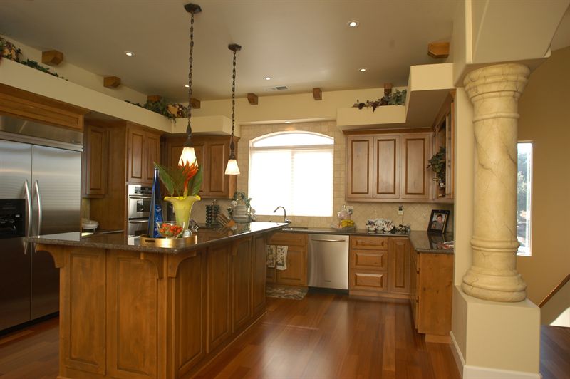 Open kitchen with wood cabinetry, island and a stone column