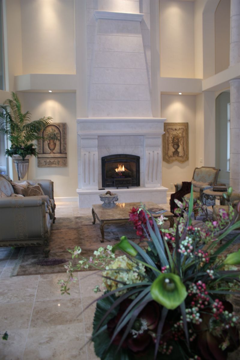 Tall living room fireplace in cast stone with a carved surround