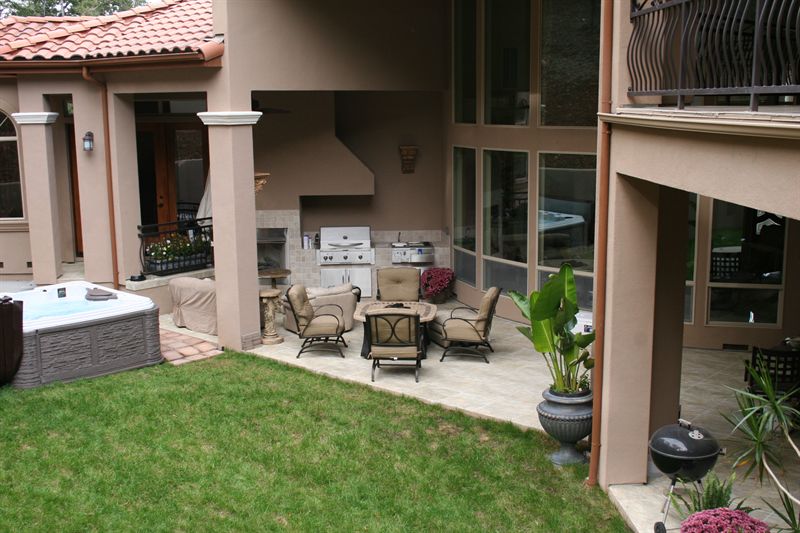 Patio with a spa, outdoor kitchen and lawn running to planting beds