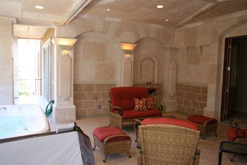 Stone-walled indoor spa room with seating and tall windows