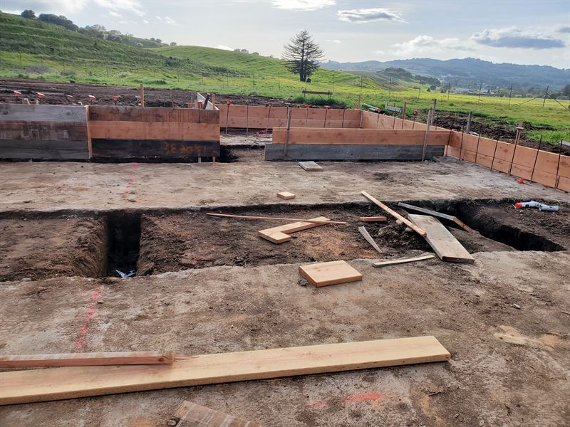 Excavated foundation trenches on a cleared lot with hills beyond