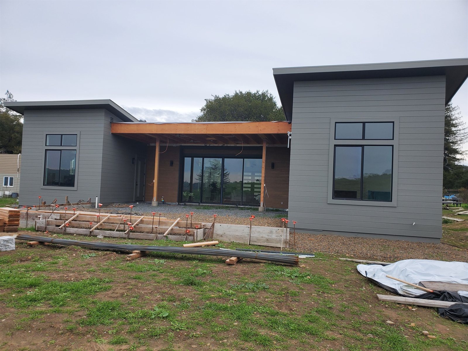 Finished single-story modern home in grey siding with a timber-lined entry