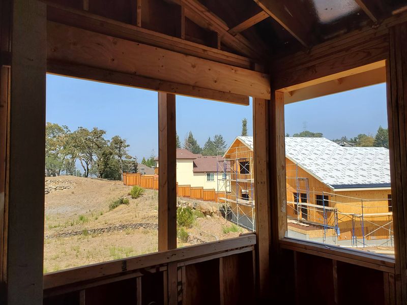 View out through a framed window opening to neighboring houses also under construction