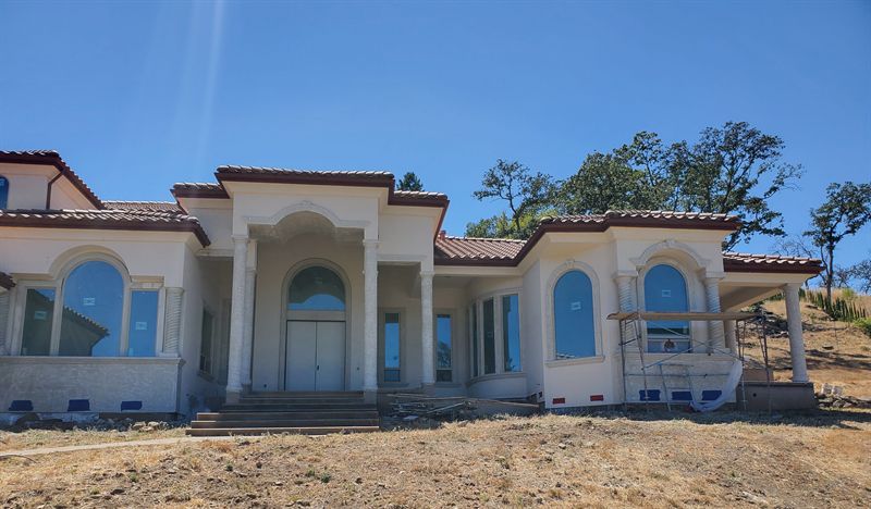 Large Mediterranean-style house with stucco complete and windows in, awaiting final finishes