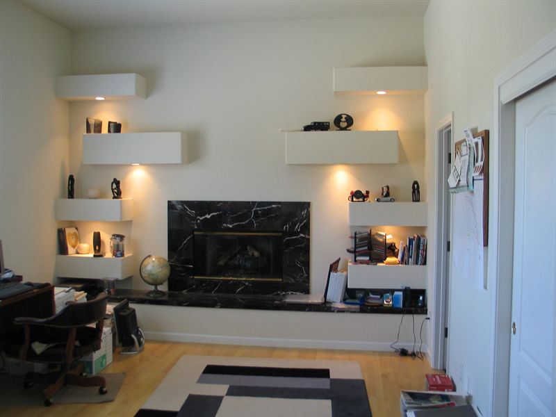 Study with a black marble fireplace and built-in floating shelving