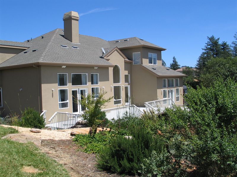 Rear elevation of a home with white balustrade decking and mature planting