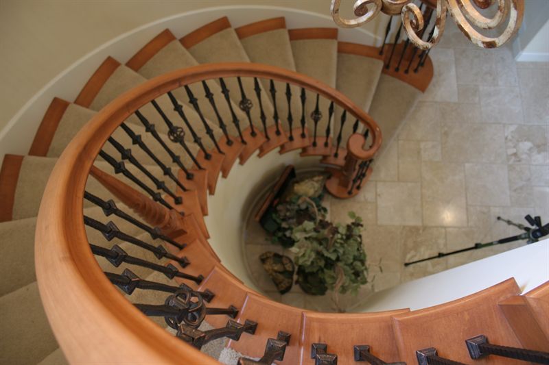 Curved staircase seen from above, with wrought iron balustrade and stone floor